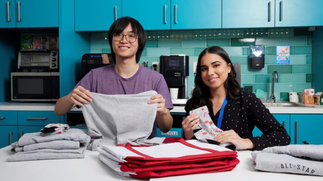 Two NCBB volunteers folding blood donor tshirts to place into a donor gift bag.