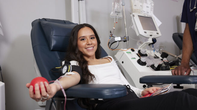 Smiling blood donor squeezing foam red heart